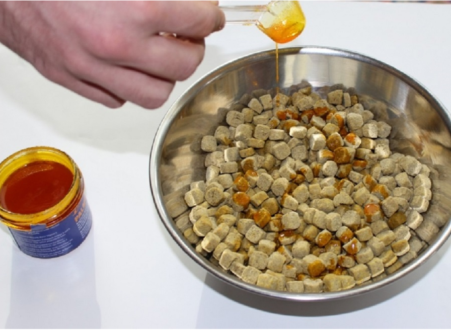 Palmgloss being poured onto Harrison's Bird Foods coarse nuggets